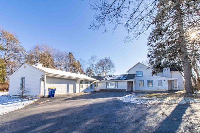 view of front of home with an attached garage, a chimney, and aphalt driveway