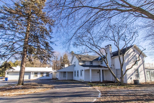 view of front of home with central air condition unit, a garage, and a chimney