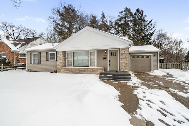 view of front of house with stone siding, fence, and an attached garage