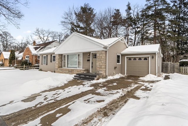 view of front of home with a garage, stone siding, and fence