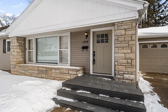 snow covered property entrance with stone siding