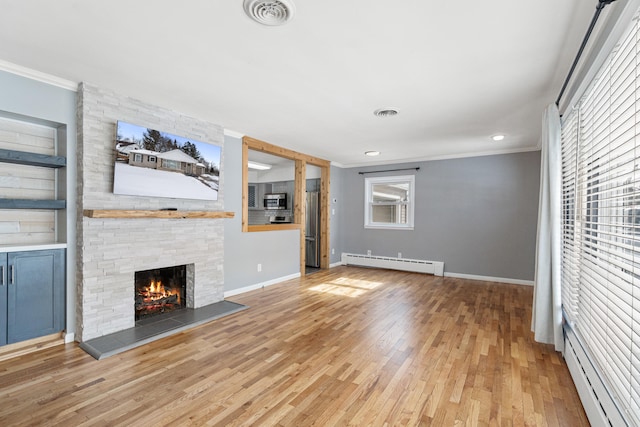 unfurnished living room featuring light wood-style floors, visible vents, a baseboard heating unit, and crown molding