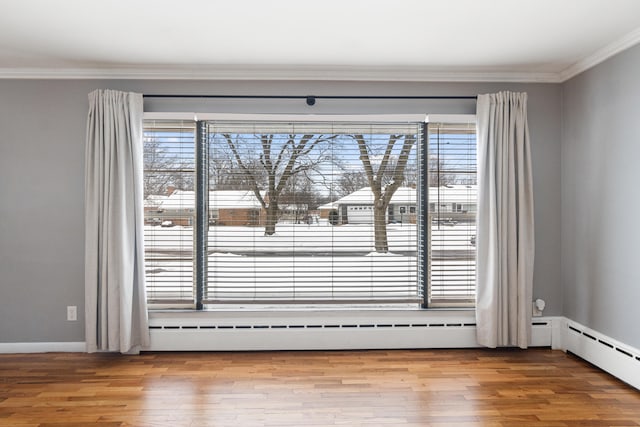 unfurnished room with baseboards, ornamental molding, baseboard heating, and wood finished floors