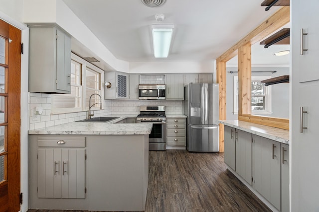 kitchen featuring light countertops, appliances with stainless steel finishes, gray cabinets, and a sink