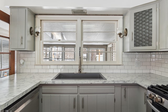 kitchen featuring a sink, stainless steel appliances, gray cabinets, light countertops, and backsplash