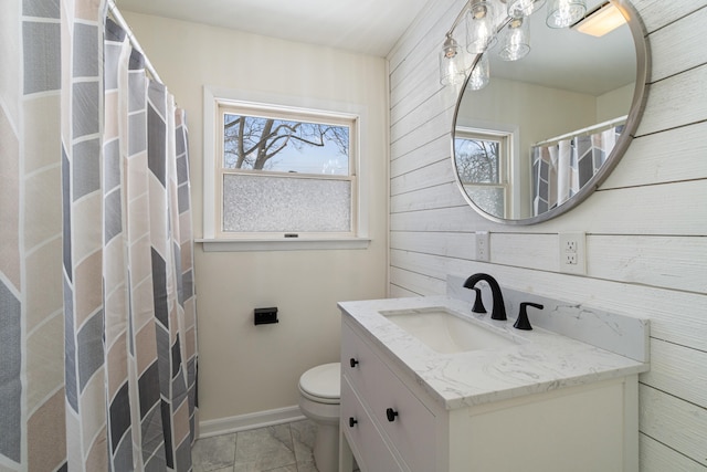 full bath with toilet, plenty of natural light, vanity, and baseboards