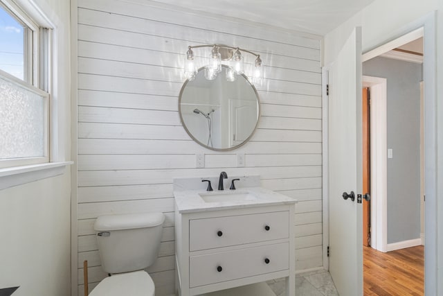 bathroom with toilet, wood walls, wood finished floors, and vanity