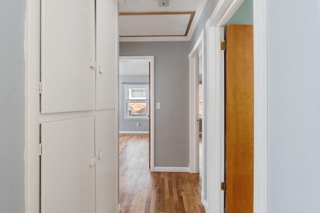 corridor featuring light wood-type flooring and baseboards