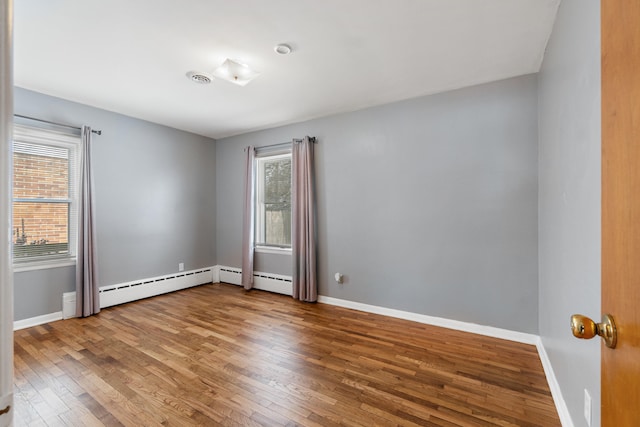 spare room with baseboards, wood finished floors, and a healthy amount of sunlight