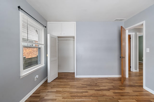 unfurnished bedroom with a closet, baseboards, visible vents, and light wood finished floors