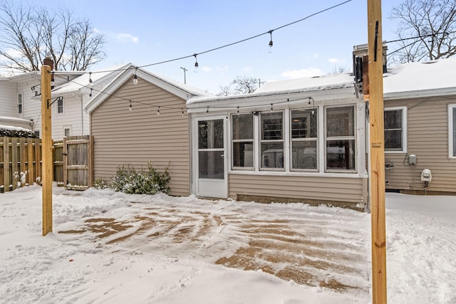 snow covered house featuring fence