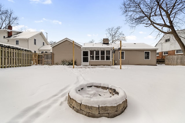 snow covered property featuring an outdoor fire pit and fence