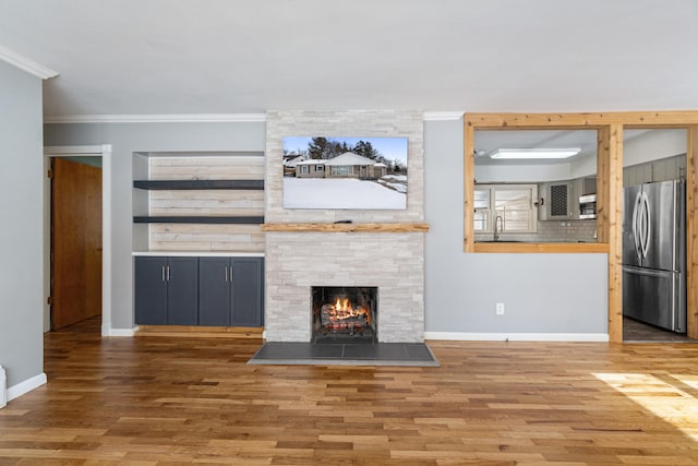 unfurnished living room with crown molding, a sink, and wood finished floors