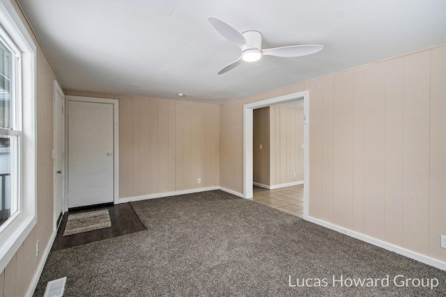 carpeted spare room with ceiling fan, plenty of natural light, and visible vents