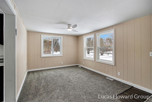 unfurnished room with baseboards, dark carpet, visible vents, and a ceiling fan