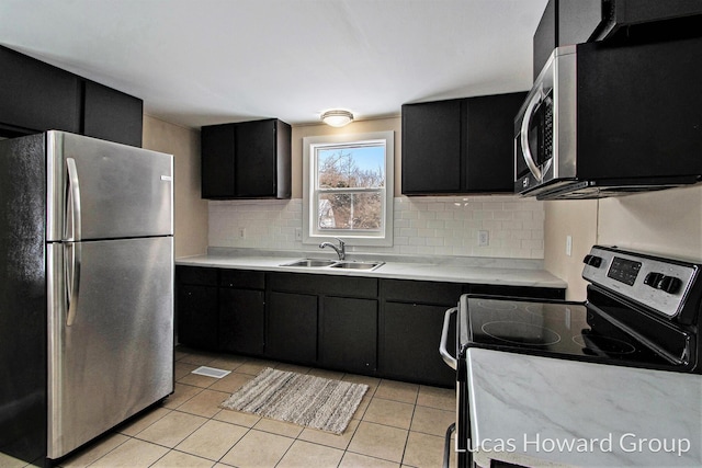 kitchen with a sink, appliances with stainless steel finishes, light countertops, and dark cabinetry