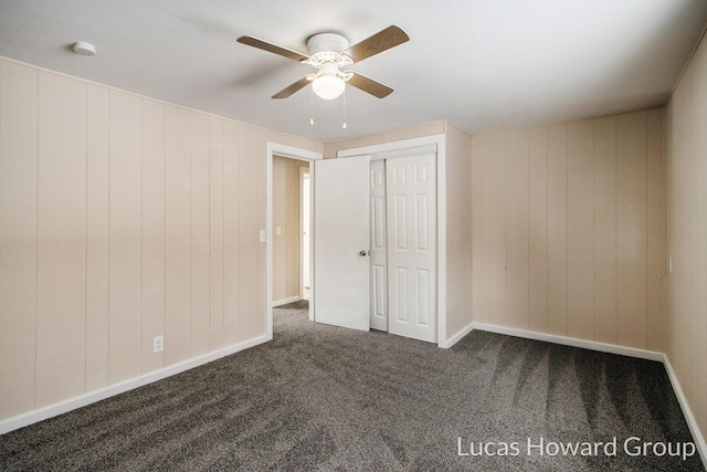 unfurnished bedroom featuring ceiling fan, dark colored carpet, a closet, and baseboards