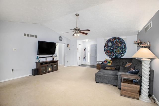 carpeted living area with lofted ceiling, visible vents, ceiling fan, and a textured ceiling