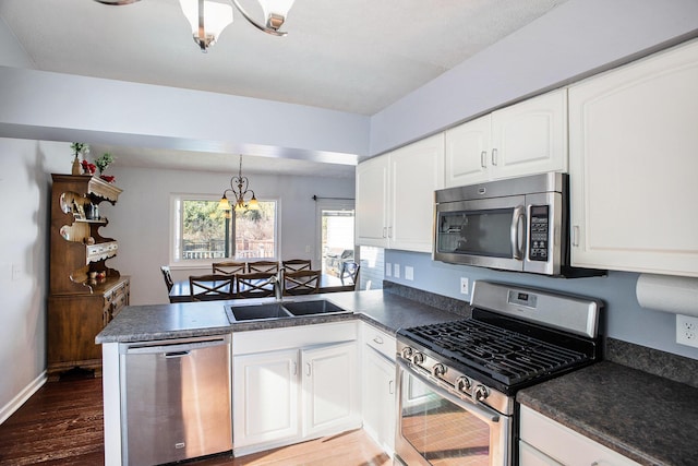 kitchen with appliances with stainless steel finishes, dark countertops, white cabinets, and a sink