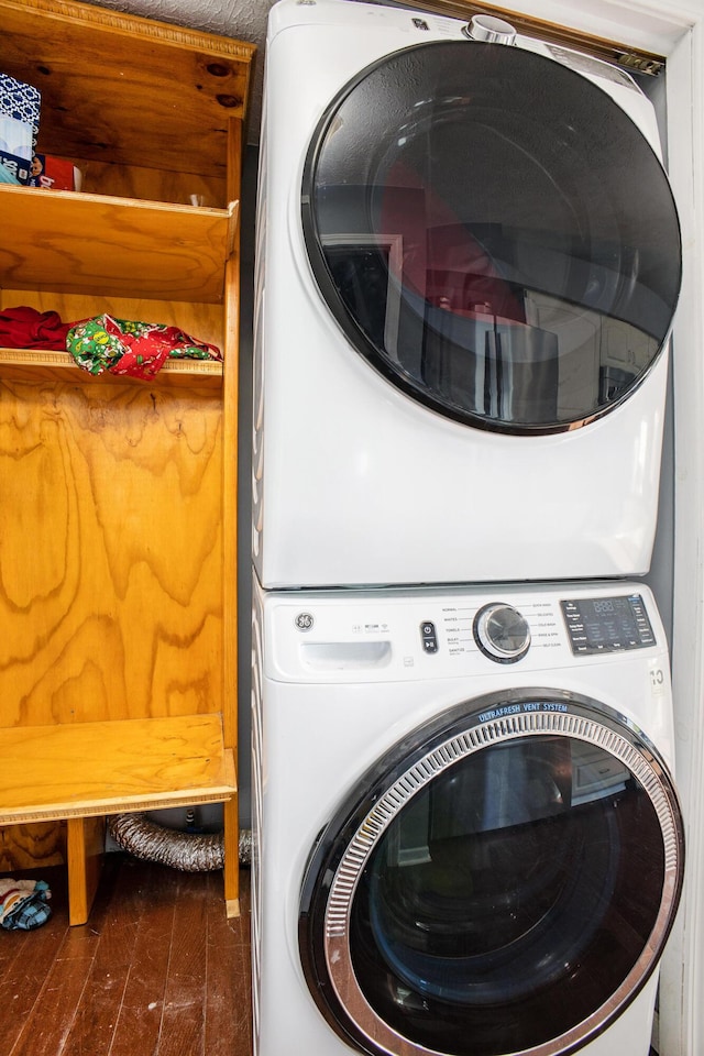 laundry room with stacked washer and dryer, dark wood-style flooring, and laundry area