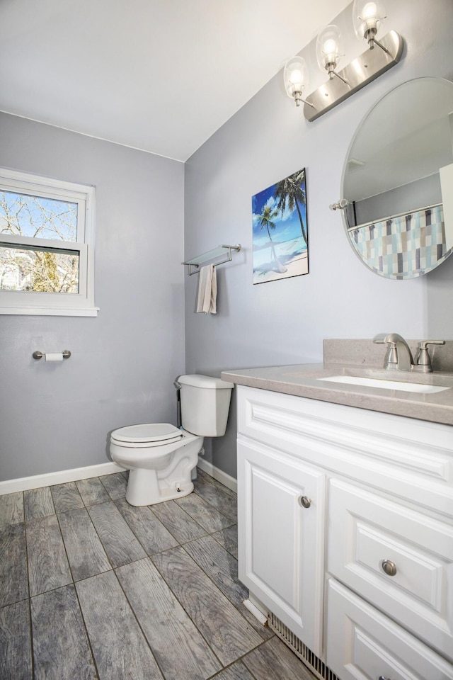 bathroom with baseboards, vanity, and toilet