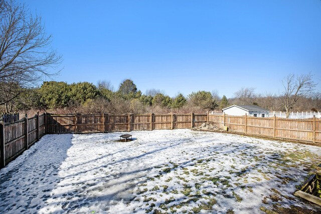 snowy yard featuring a fire pit and a fenced backyard