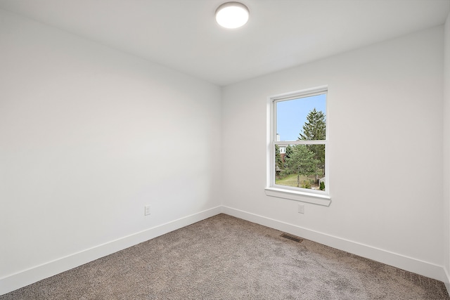 empty room featuring carpet, visible vents, and baseboards