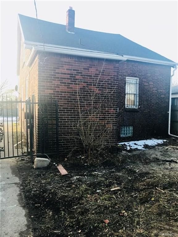 view of property exterior featuring brick siding and fence