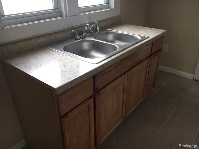 kitchen with brown cabinets, baseboards, light countertops, and a sink