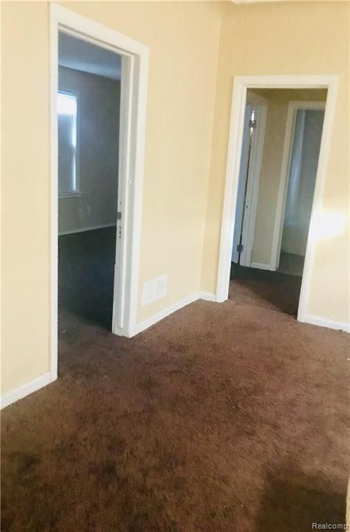 spare room with dark carpet and baseboards