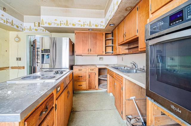 kitchen featuring stainless steel appliances, light countertops, brown cabinetry, and a sink