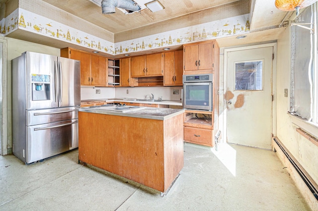 kitchen with brown cabinetry, appliances with stainless steel finishes, baseboard heating, and a center island