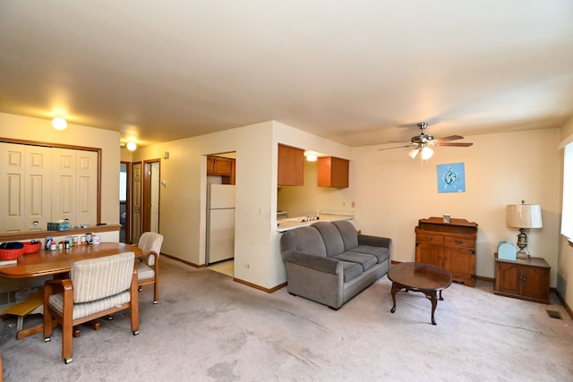 living area with a ceiling fan, visible vents, light carpet, and baseboards