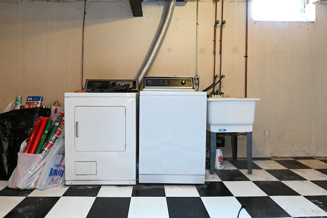 laundry room with laundry area, washing machine and dryer, dark floors, and a sink