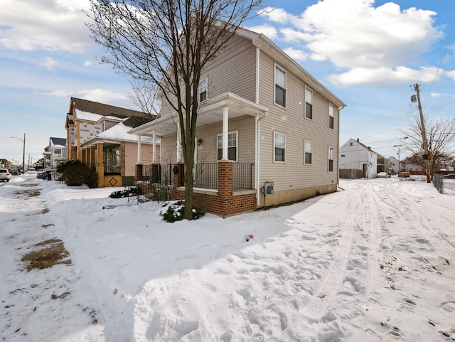 snow covered property featuring a porch and a residential view