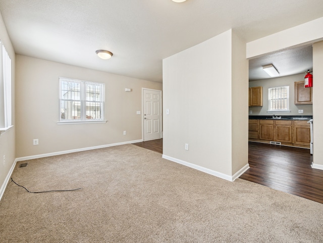 spare room with dark carpet, visible vents, and baseboards