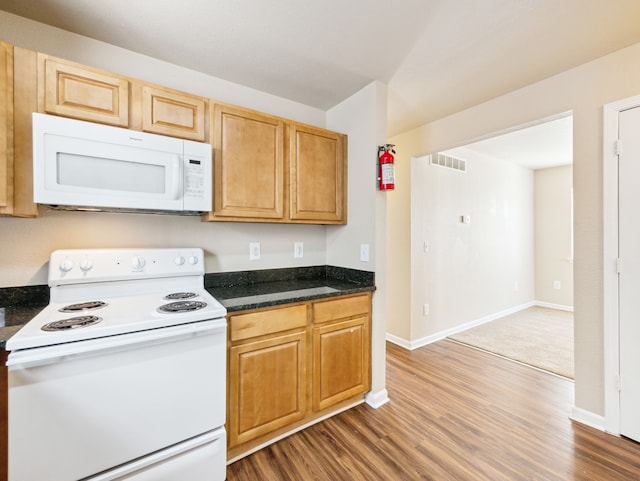 kitchen with white appliances, baseboards, visible vents, and wood finished floors