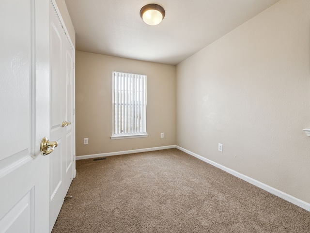 carpeted empty room with visible vents and baseboards