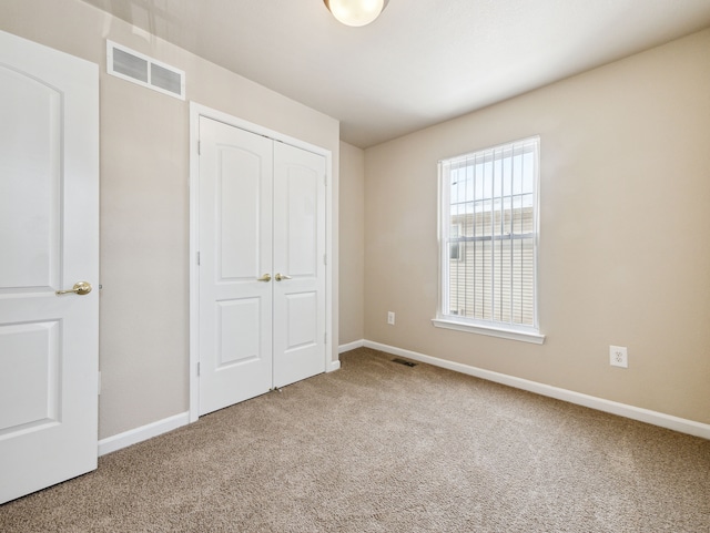 unfurnished bedroom featuring carpet floors, a closet, visible vents, and baseboards