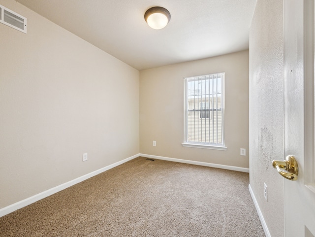 empty room featuring carpet floors, baseboards, and visible vents