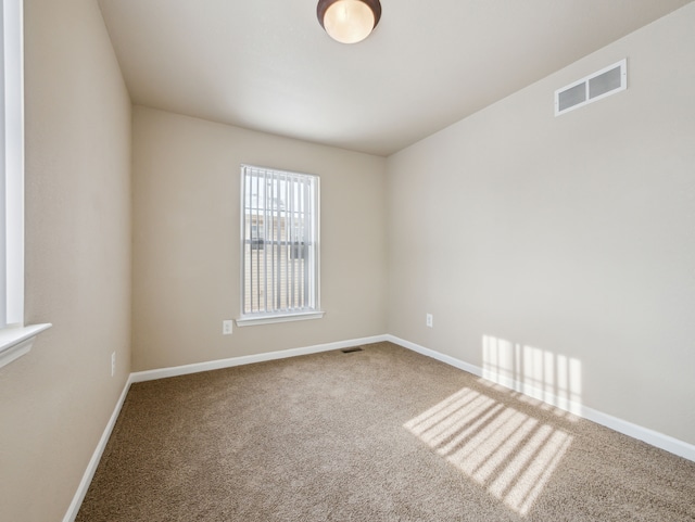 unfurnished room with carpet, visible vents, and baseboards