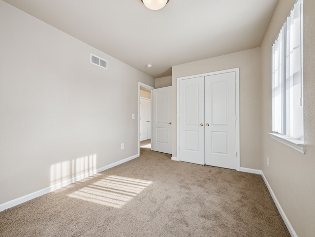 unfurnished bedroom featuring a closet, carpet flooring, visible vents, and baseboards