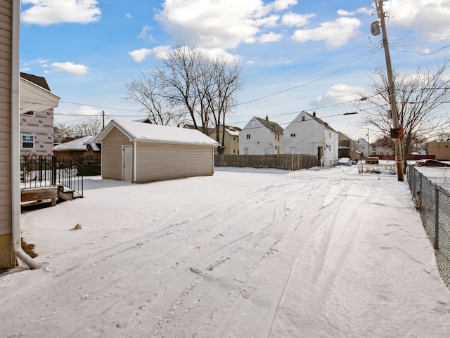 yard layered in snow with an outbuilding, a shed, fence, and a residential view