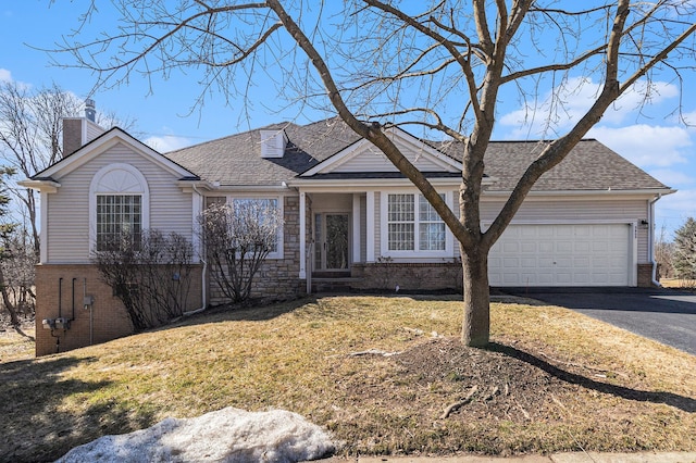 view of front of home featuring brick siding, a shingled roof, a front lawn, aphalt driveway, and a garage