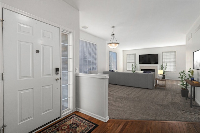 foyer entrance with baseboards, dark wood finished floors, and a fireplace