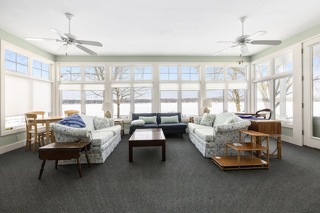 sunroom featuring a healthy amount of sunlight, ceiling fan, and a water view