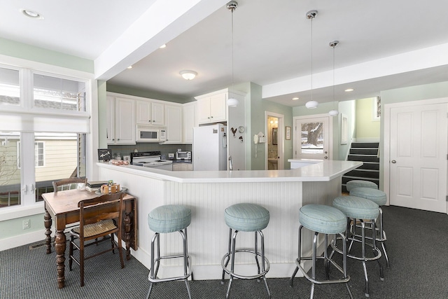 kitchen with white appliances, white cabinets, light countertops, plenty of natural light, and decorative light fixtures