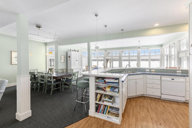 kitchen with white cabinets, dishwasher, decorative light fixtures, a healthy amount of sunlight, and a sink