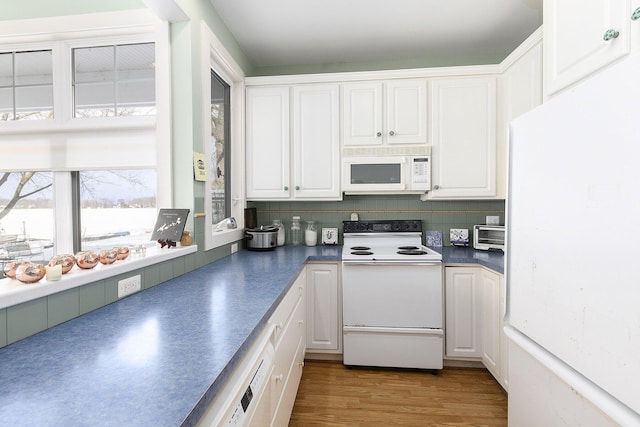 kitchen featuring white appliances, wood finished floors, white cabinetry, decorative backsplash, and dark countertops