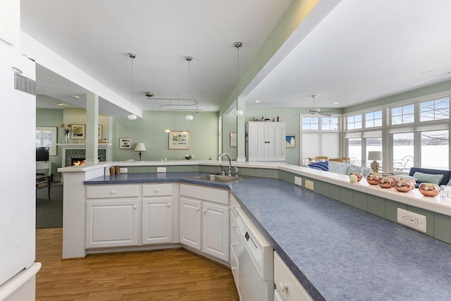 kitchen featuring white cabinets, white dishwasher, open floor plan, and a sink